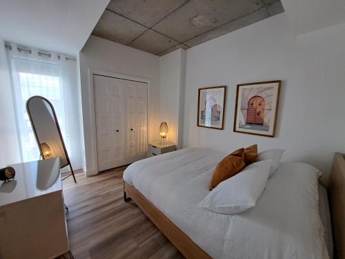 een witte slaapkamer met een bed en een raam bij Le 908, suberbe condo neuf avec piscine in Québec