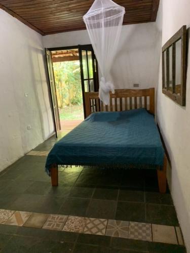 ein Schlafzimmer mit einem Bett mit einer blauen Decke darauf in der Unterkunft Chalés Bambá in Ilhabela