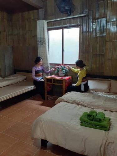 two women sitting on beds in a room at Thao Ly Homestay Mai Chau in Hòa Bình