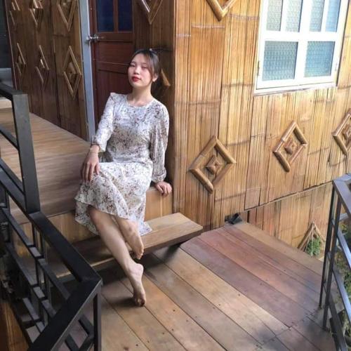 a woman sitting on a wooden bench in a house at Thao Ly Homestay Mai Chau in Hòa Bình