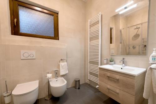 uma casa de banho com um WC, um lavatório e um espelho. em Dolce Far Niente Apartment with pool & parking em Passignano sul Trasimeno