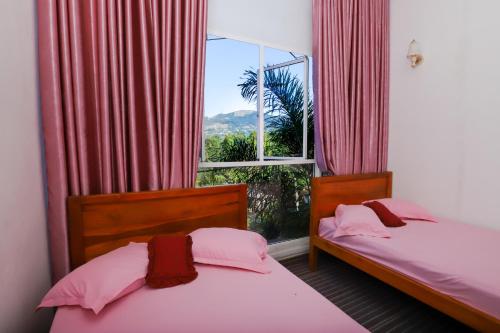 2 Einzelbetten in einem Zimmer mit Fenster in der Unterkunft DELIGHT REICH HOTEL in Peradeniya