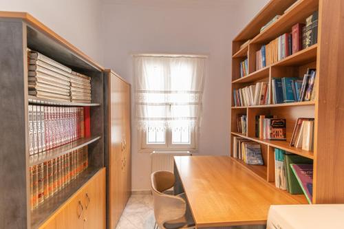 um quarto com uma mesa de madeira e prateleiras de livros em Evangelia's Mansion em Naxos Chora