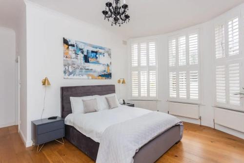 a bedroom with a bed with white walls and windows at Luxury 2 Bedroom Apartment with gym in London