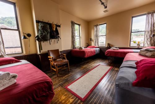 a room with three beds and a chair and windows at Traveler's Rest Hotel in Pittsburgh