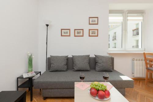 een woonkamer met een bank en een tafel met wijnglazen bij Cozy Studio in the Heart of Warsaw, Elektoralna by Renters in Warschau