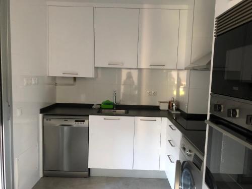a white kitchen with white cabinets and a dishwasher at TÍA NANDUCA in Liencres