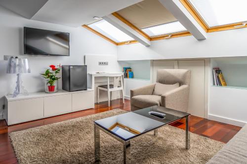 ein Wohnzimmer mit einem TV, einem Sofa und einem Tisch in der Unterkunft Hotel Apolonia Soria in Soria