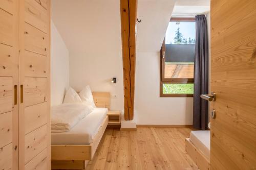 Nigglhof Apartment Maria في Redagno: غرفة نوم صغيرة بها سرير ونافذة