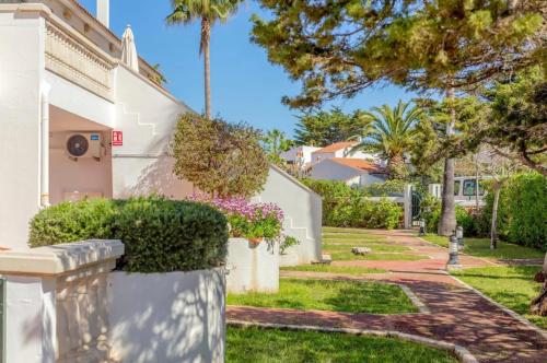 una casa con arbustos y árboles en un patio en Bonito apartamento con terraza, jardín y piscina en Cala'n Bosch