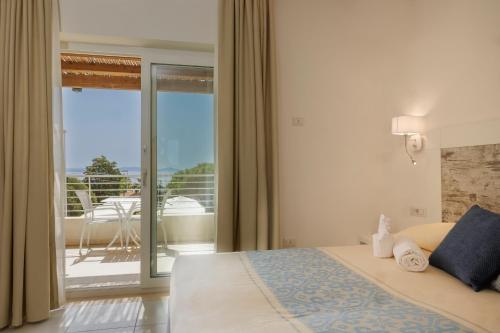 um quarto com uma cama e vista para uma varanda em Mercury Beach Hotel em SantʼAntìoco