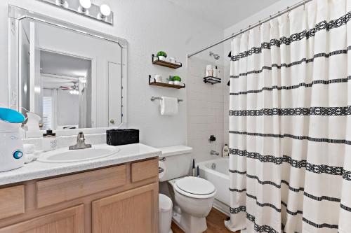 a bathroom with a sink and a toilet and a shower curtain at The Val's Place in Houston
