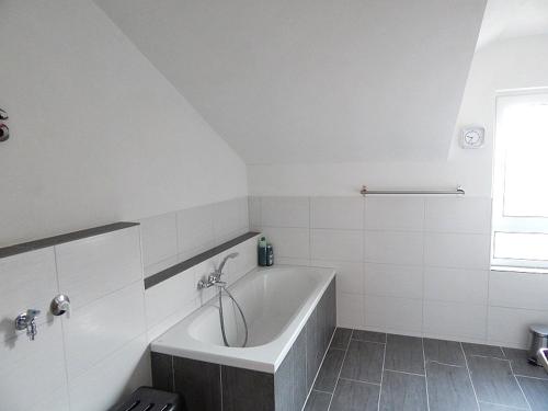 baño blanco con bañera y ventana en Ferienwohnungen Bergidyll en Sachrang
