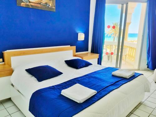 um quarto azul com uma cama com lençóis azuis e uma janela em Hotel Neptunia Skanes em Monastir