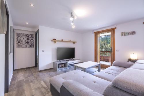 un salon avec deux canapés et une télévision à écran plat dans l'établissement Le Samance 2, au Grand-Bornand