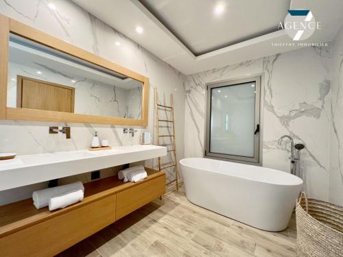 une salle de bain avec une grande baignoire et un grand miroir dans l'établissement Villa Pomme d'Amour, à Sainte-Maxime