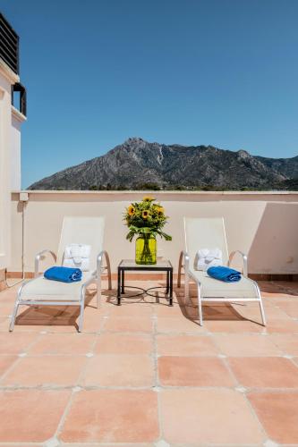 two chairs and a table with a vase of flowers at Guadalpin Suites in Marbella
