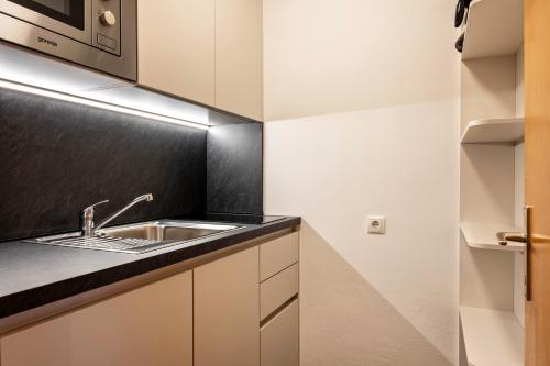 uma cozinha com armários brancos e um lavatório em Appartement Schlern Living 1 em Fiè