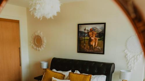 グラスゴーにあるLovely Bohemian Apartment in Heart of City Lifeの壁に絵画が描かれたベッドルーム、ソファが備わります。