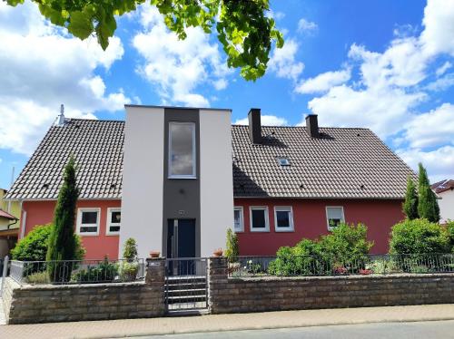 a red and white house with a brick wall at Ferienwohnung an der Klinge in Wiesenbronn