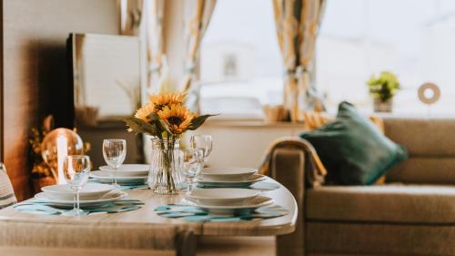 uma mesa com pratos e copos e um vaso de flores em Cosy Caravan Craig Tara em Ayr