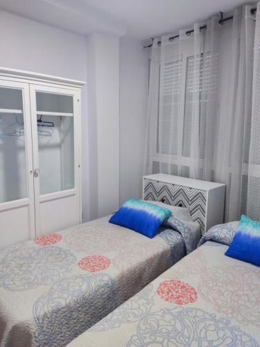 Un dormitorio con dos camas con almohadas azules. en Apartamentos a 300 metros playa, en Roquetas de Mar