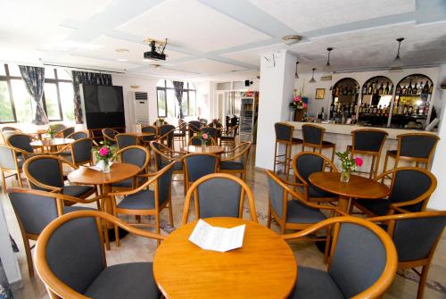 un restaurante con mesas y sillas de madera y un bar en Aegeon Hotel - Adults Only en Cos