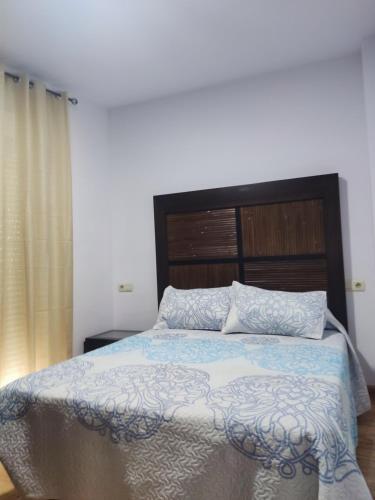 um quarto com uma cama grande e uma cabeceira em madeira em Apartamentos el rebalaje III em Roquetas de Mar