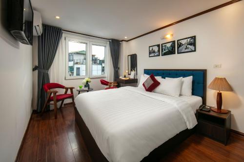 a bedroom with a large white bed and a desk at Silk Flower Hotel & Spa in Hanoi
