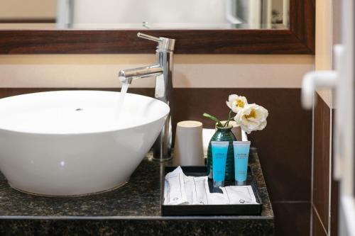 a bathroom counter with a sink and flowers and toothpaste at Silk Flower Hotel & Spa in Hanoi