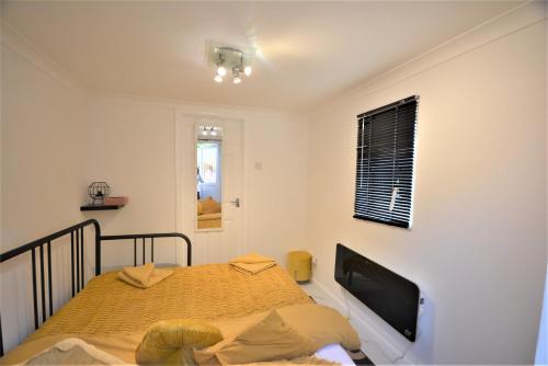 a bedroom with a bed and a flat screen tv at Adorable 1 bedroom guest house with free parking. in Bromley