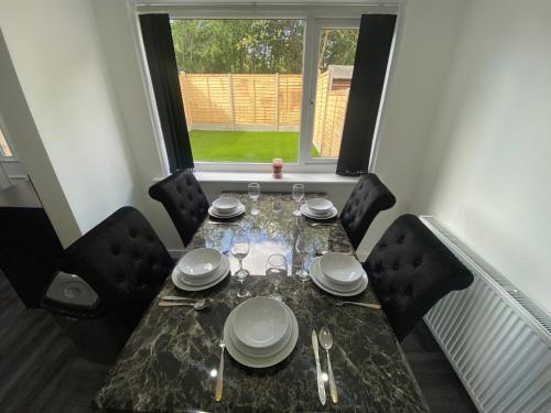 a dining room table with plates and silverware on it at Modern 3 Bedroom Holiday Home -Jaquzzi Bath -Private Parking-suitable for contractors - Free WiFi in Beeston