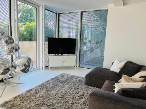 een woonkamer met een bank en een flatscreen-tv bij FeWo Silberberg im Loftstil mit Terrasse in Leonberg