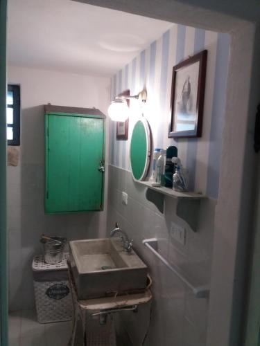 La salle de bains est pourvue d'un lavabo et d'une armoire verte. dans l'établissement TRULLO PIETRAPOESIA, à Ostuni