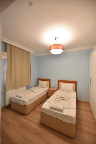 two twin beds in a room with a light at Caretta Apart in Fethiye