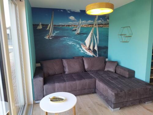 a living room with a couch and a painting of sailboats at Ferienhof Dachsberg Wohnung Maritim in Bermatingen