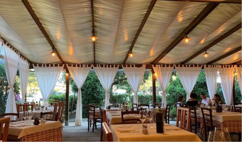 uma sala de jantar com mesas e cortinas brancas em Marina di Bibbona - Lotto B em Marina di Bibbona
