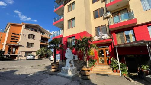 a building with a statue in front of a street at Хотел Свищов спа зона in Svishtov