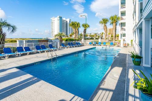a swimming pool with blue chairs and a building at Grande Caribbean in Orange Beach