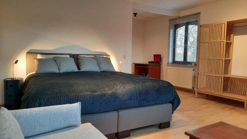 a bedroom with a large bed and a couch at The Kettle House - Manor in Sint-Pieters-Leeuw