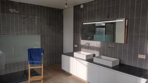 a bathroom with two sinks and a mirror and a blue chair at The Kettle House - Manor in Sint-Pieters-Leeuw