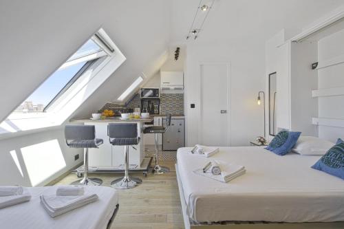 Cette chambre mansardée comprend deux lits et une cuisine. dans l'établissement Studio de l'Abbé - Biarritz - Welkeys, à Biarritz