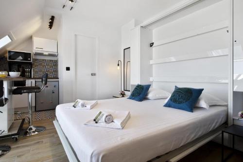 een slaapkamer met een groot wit bed met blauwe kussens bij Beautiful modern studio with a view on the ocean - Biarritz - Welkeys in Biarritz