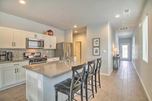 a kitchen with white cabinets and a island with chairs at Family-Friendly Rio Rancho Home Near Old Town in Rio Rancho