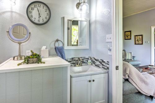 ein Badezimmer mit einem Waschbecken und einer Uhr an der Wand in der Unterkunft Secluded Weatherford Cottage with Outdoor Pool! in Willow Park