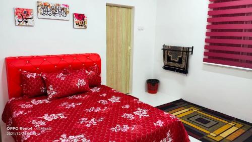 Kampong Bota RoadにあるRania Homestay With Private Pool Seri Iskandar Perak Near UTP UITMの赤いベッド1台(赤い掛け布団付)が備わるベッドルームです。