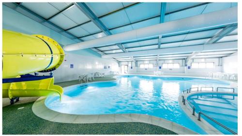 a large pool with a water slide in a building at Willow-Static Caravan on Holiday Park near Margate, Kent in Kent