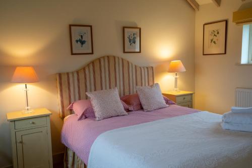 a bedroom with a large bed with two lamps at The Calf Shed - cozy cottage in peaceful Norfolk countryside in Aldeby