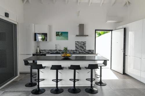 a kitchen with a black counter and stools at Villa La Vue - Vue panoramique sur les lagons in Gustavia