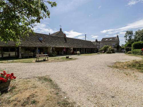 a gravel road in front of a building with a bench at Tump Cottage in Nympsfield